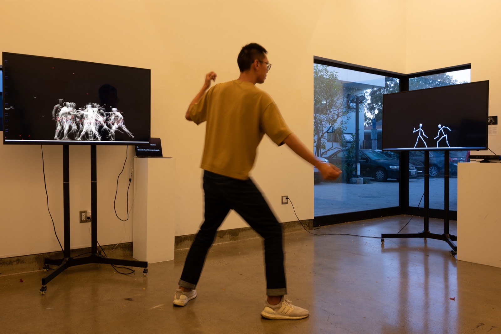 A visitor mid-lunge between two screens, one showing the paired skeletons and the other the accumulated chronophotograph