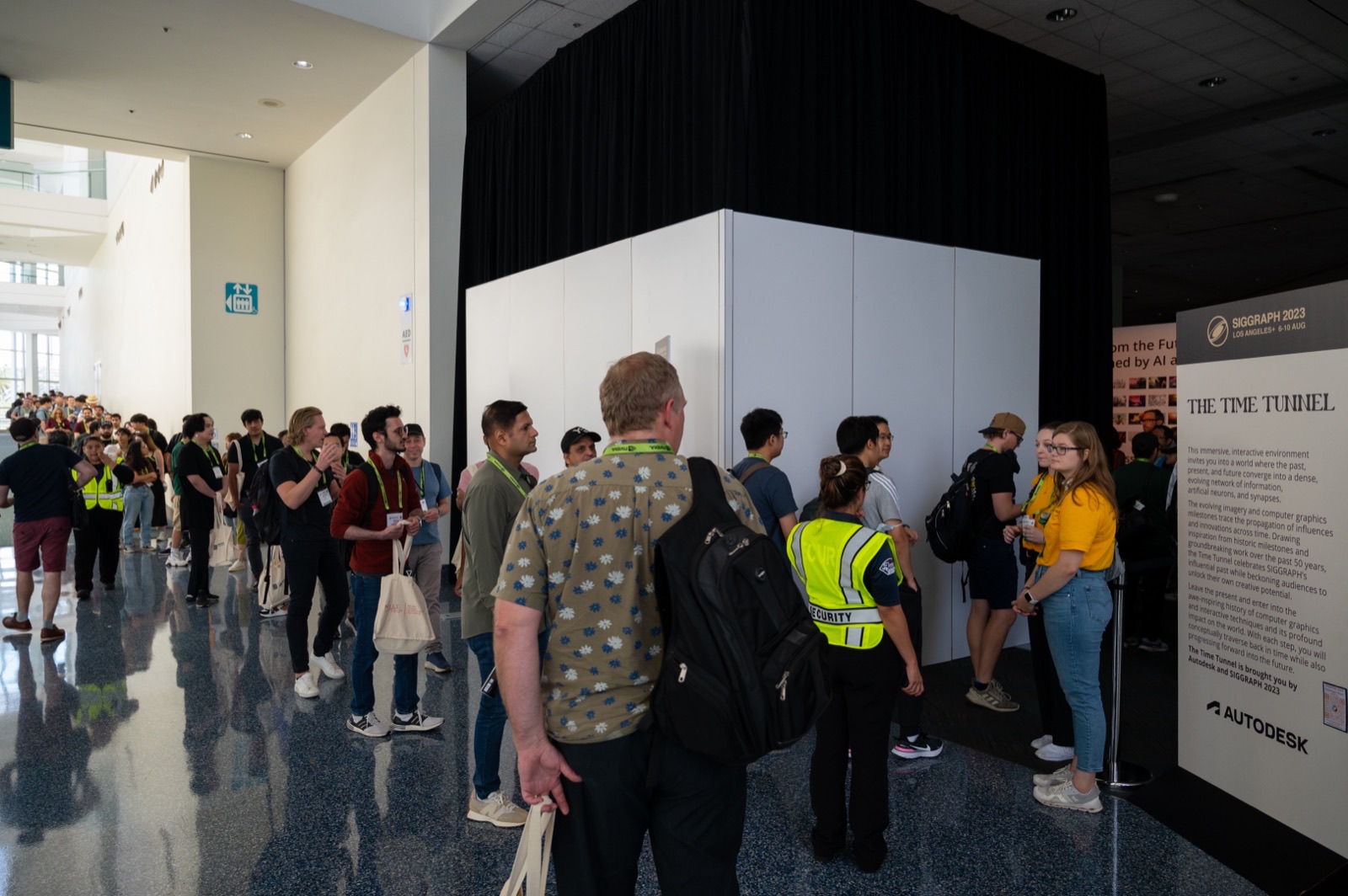 Visitors queueing at the entrance of the Time Tunnel, beside a wall panel carrying the exhibition text and the Autodesk and SIGGRAPH 2023 logos