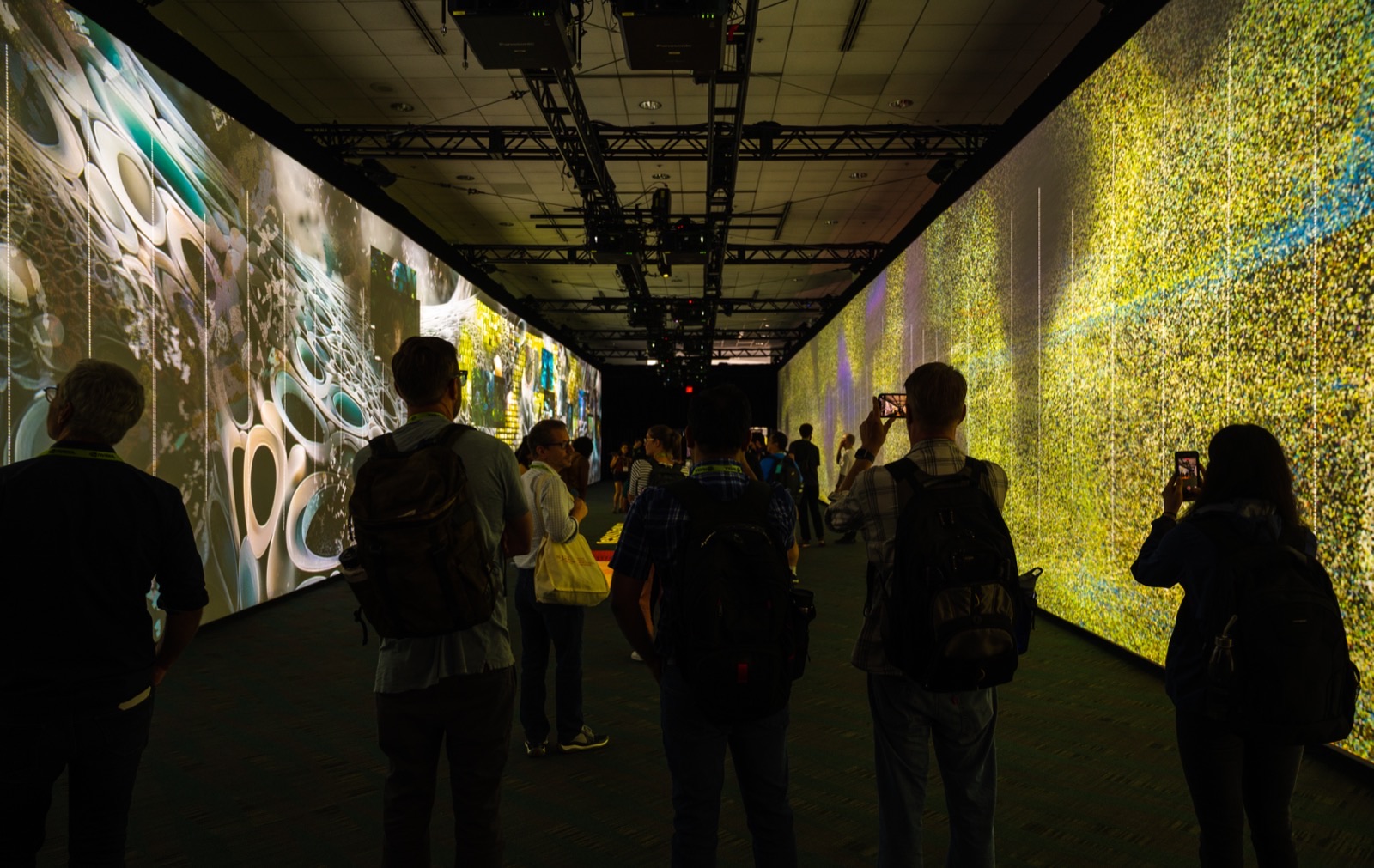 The corridor seen end-on, LED walls on both sides, visitors photographing the imagery