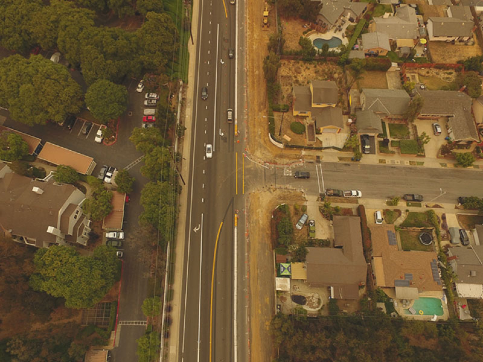 Straight-down aerial frame of a highway cutting between woodland and a suburban block, one of the field-test captures